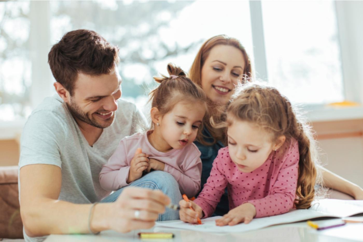 Mum and Dad with two daughters smiling and drawing
